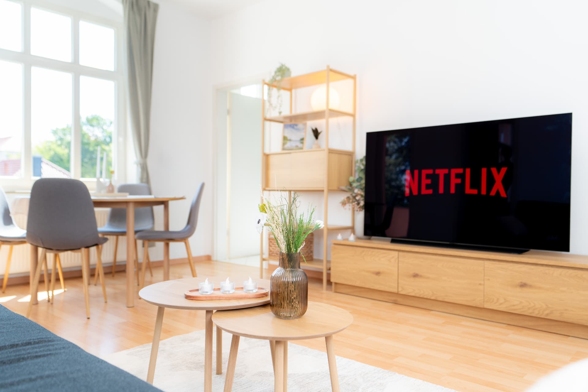 Heller Wohnbereich mit Esstisch, Holzmöbeln und Fernseher in einer möblierten Wohnung